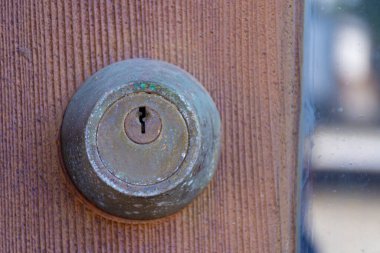 Eski paslı, eski bir kapı kilidinin kaba ahşap bir kapı çerçevesi üzerindeki yakın plan görüntüsü.. 