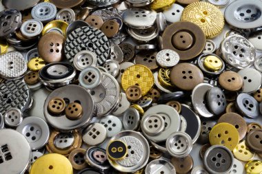 Kıyafet aksesuarları için kullanılan parlak metal düğmelerin soyut bir görüntüsü.. 