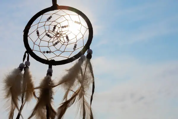 stock image A silhouette  image of a handmade dreamcatcher against golden sun rays and blue sky. 