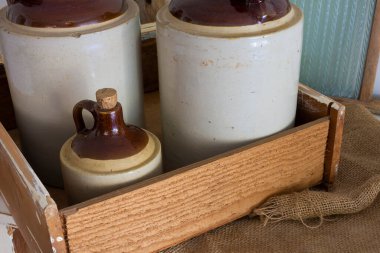 Eski ahşap bir sandıkta paketlemek için çuval bezi olan üç adet eski seramik viski sürahisi..