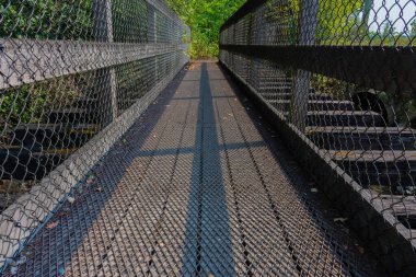 Düşük açılı, koruyucu metal ızgaralı çok eski bir tahta ayak köprüsünün görüntüsü.. 