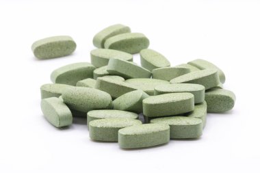 Beyaz arka planda yığılmış çok büyük yeşil vitamin hapları..