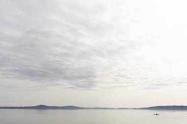 Sakin göl sularında sabahın erken saatlerinde bir kanocunun görüntüsü.. 