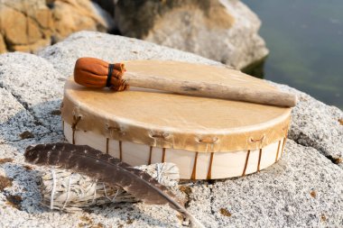 Beyaz adaçayı lekeli ve kutsal tüyü olan el yapımı bir deri meditasyon davulu..