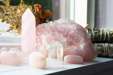 Beyaz pencere kenarında çeşitli gül kuvars kristalleri ve beyaz adaçayı lekeleri var..
