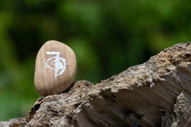 Düzgün cilalanmış bir kayanın üzerine Reiki şifa sembolü çizilmiş.. 