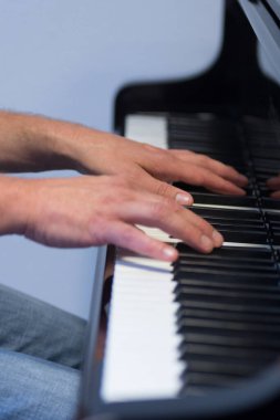 Piyano çalarken insan elleri klasik siyah bir piyanoda nota ve akorlar çalıyor.