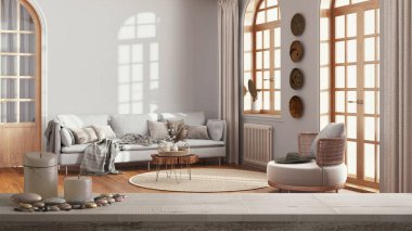 Wooden vintage table top or shelf with candles and pebbles, zen mood, over farmhouse living room with rattan furniture, white architecture interior design