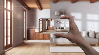 El ele tutuşan akıllı telefon, AR uygulaması, gerçek evde mobilya ve iç tasarım ürünleri simülasyonu, mimar tasarım konsepti, bulanık arka plan, oturma odası ve mutfak