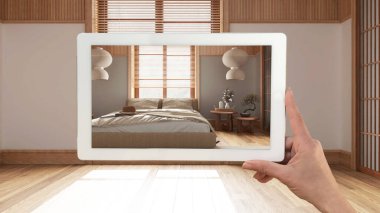 Gelişmiş gerçeklik kavramı. El ele tutuşma tableti ve AR uygulaması parke zeminli, japandi yatak odalı boş iç döşemeli mobilya ve tasarım ürünleri simülasyonunda kullanılır.