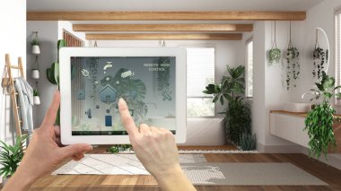 Dijital tablette akıllı uzaktan kumanda sistemi. Uygulama simgeleri olan aygıt. Küvetli modern banyo ve birçok ev bitkisi, kentsel orman iç tasarımı