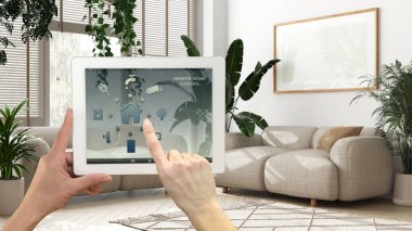 Dijital tablette akıllı uzaktan kumanda sistemi. Uygulama simgeleri olan aygıt. Ev bitkileriyle ahşap, en az beyaz oturma odası, kentsel orman iç tasarımı.