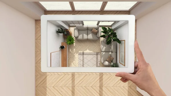 Augmented reality concept. Hand holding tablet with AR application used to simulate furniture and design products in empty wooden interior, urban jungle living room, top view, plan