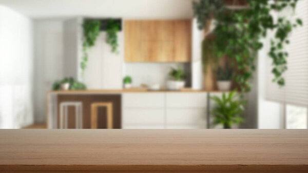 Empty wooden table, desk or shelf with blurred view of minimal white and wooden kitchen with island and many houseplants. Urban jungle interior design concept