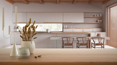 Ahşap masa, masa ya da raf seramik ve cam vazolarla kaplanmış kuru bitkiler, yemek adalı minimalist mutfağın bulanık görüntüsü, modern iç tasarım konsepti