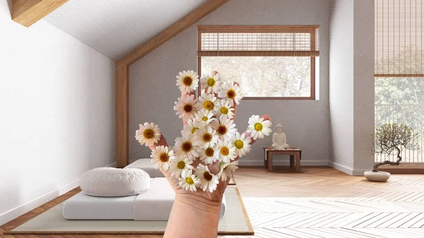Woman\'s hand holding daisies, spring and flowers idea, over japandi meditation room, wooden roof ceiling, tatami, resin floor, interior design idea