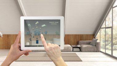 Dijital tablette akıllı uzaktan kumanda sistemi. Uygulama simgeleri olan aygıt. Arka planda modern asgari Mansard oturma odası, mimari iç tasarım