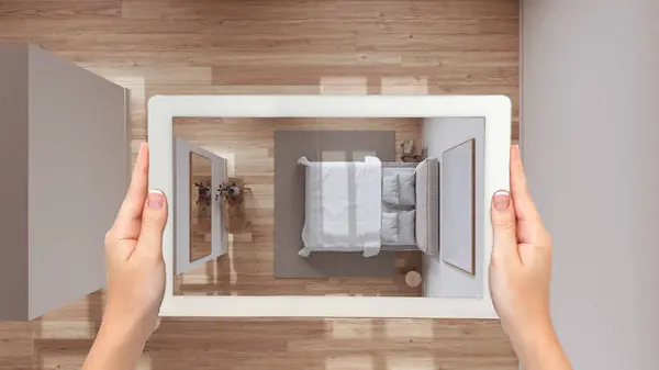 Augmented reality concept. Hand holding tablet with AR application used to simulate furniture and design products in total white unfinished background, d bedroom top view