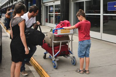 Aile bavullarını havaalanında bir el arabasına yüklüyor.