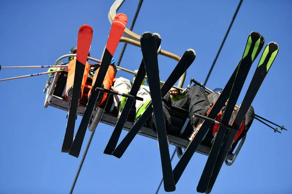 Kayakçılar dağlarda kayaklarla teleferiğe tırmanıyorlar.