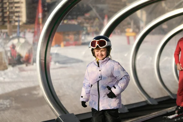 スキーの女の子がトンネルのカーペットスキーリフトの上に立っている — ストック写真