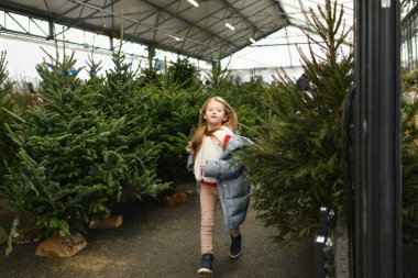 Noel ağaçlarının arasında koşan bir kız