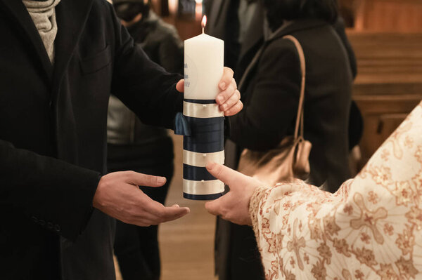 Священник зажигает свечу для обряда крещения