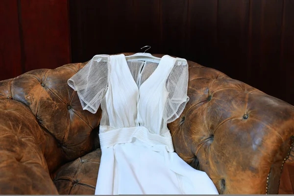 ウェディングドレスはヴィンテージブラウンの革の椅子にあります — ストック写真
