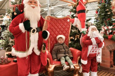 Şapkalı bir çocuk Noel Baba 'yı dükkanda ziyaret ediyor.