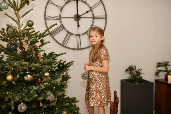Seorang Gadis Dalam Gaun Emas Menghias Pohon Natal Stok Gambar