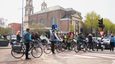 AMSTERDAM, NETHERLANDS - 16 Nisan 2019: Bisikletli bisikletçiler yeşil ışık için bekliyorlar