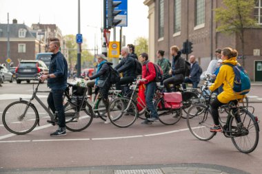 AMSTERDAM, NETHERLANDS - 16 Nisan 2019: Bisikletli bisikletçiler yeşil ışık için bekliyorlar