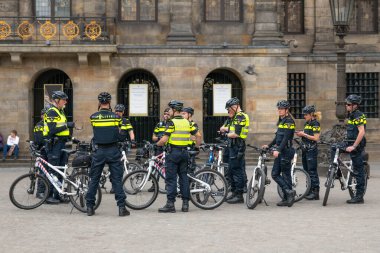 AMSTERDAM, NETHERLANDS - 16 Nisan 2019: bisikletli üniformalı polis memurları düzeni koruyorlar. Şehrin merkezinde güvenlik kamerası var..