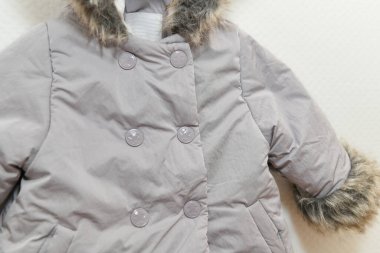 Beyaz arka planda asılı duran kız için gri-leylak renkli kürk ceket