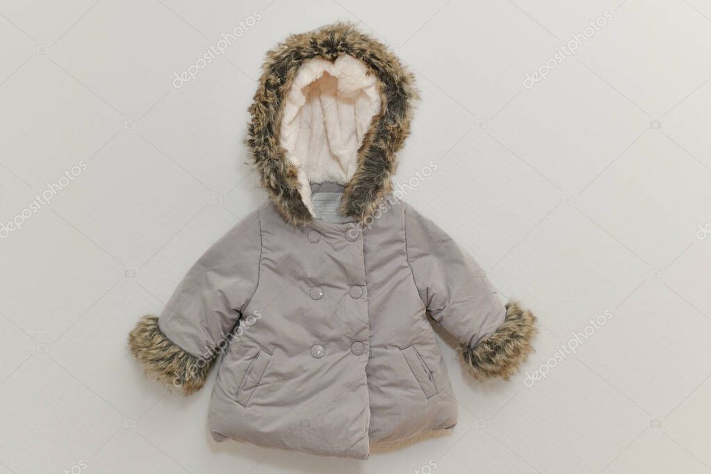 Grey-lilac colored fur jacket for girl hanging on hanger on white background