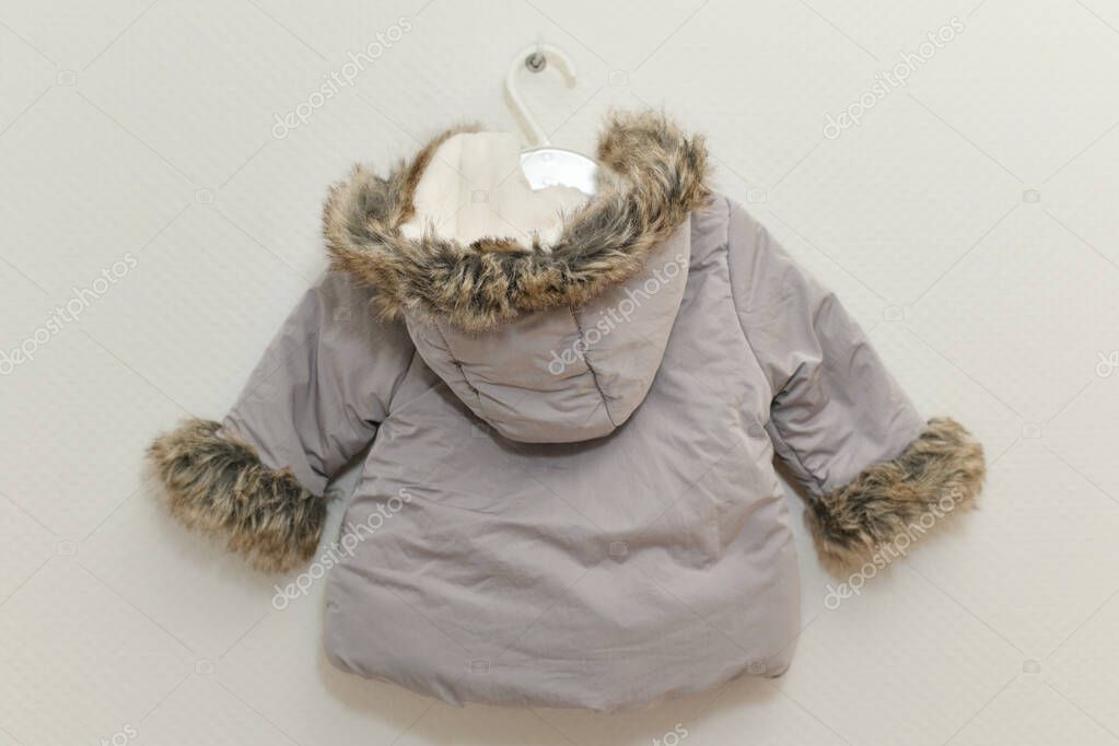 Grey-lilac colored fur jacket for girl hanging on hanger on white background