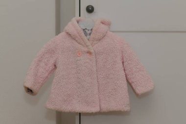 Beyaz arka planda asılı pembe kış kürkü ceketi.