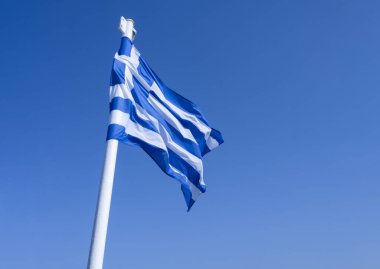 Mavi ve beyaz Yunan bayrağı mavi gökyüzünde dalgalanıyor