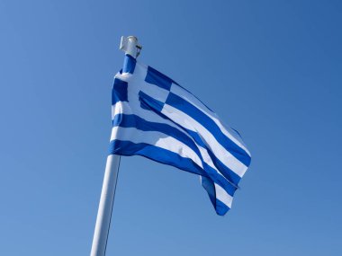 Mavi ve beyaz Yunan bayrağı mavi gökyüzünde dalgalanıyor