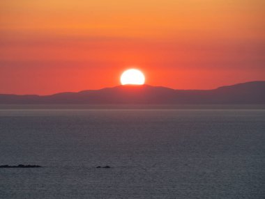 Güneş, Yunanistan 'daki Mykonos adasının manzarası olan Syros adasının arkasında batıyor