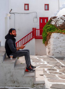 Yunanistan 'daki Mykonos adasının simgelerinden biri olan Ortodoks Paraportiani Kilisesi' nde bir adam oturuyor.