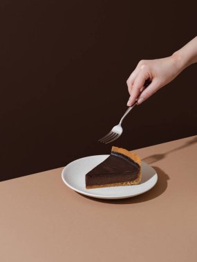 Piece of drk chocolate cheesecake on beige and brown background. Minimalist food photography 