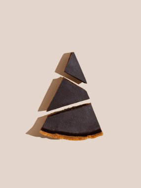 Pieces of drk chocolate cheesecake on beige and brown background. Minimalist food photography 