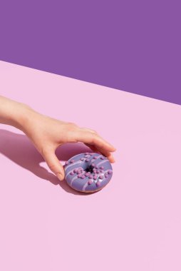 Renkli arka planda lezzetli bir donutla bir el.