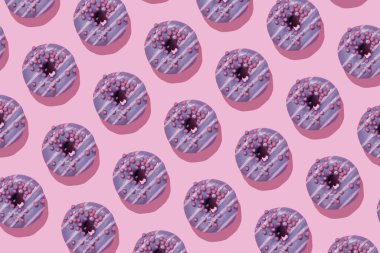 Donut deseni. Pembe arka planda serpiştirilmiş renkli donutlar.