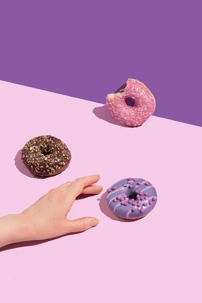 Eine Hand Mit Einem Leckeren Donuts Auf Einem Farbigen Hintergrund — Stockfoto