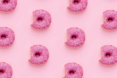 Donut deseni. Pembe arka planda serpiştirilmiş pembe jöleli donutların üst görüntüsü