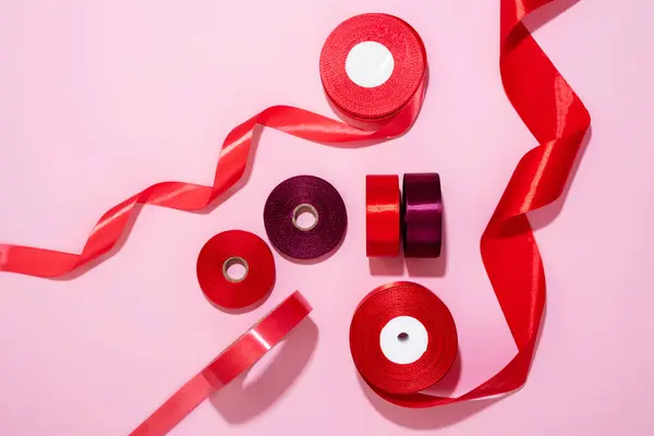 Set Red Satin Ribbon Spools Pink Background Textile Ribbon Reels — Stock Photo, Image