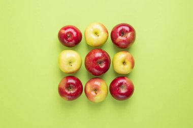 Açık yeşil arka planda bir meydana yerleştirilmiş renkli elmalar. Yaz ya da sonbahar meyvesi, lezzetli ve sağlıklı atıştırmalıklar. Yaratıcı gıda konsepti. Üst görünüm, alanı kopyala