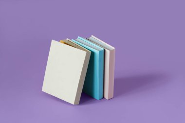 Pastel mor arka planda yumuşak gölgeli üç renkli kitap, kopyalama alanı. Eğitim, Eğitim ve Kitap Aşıkları Günü konsepti